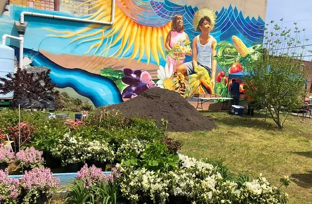 A yard with a flower garden in front of a large wall mural.